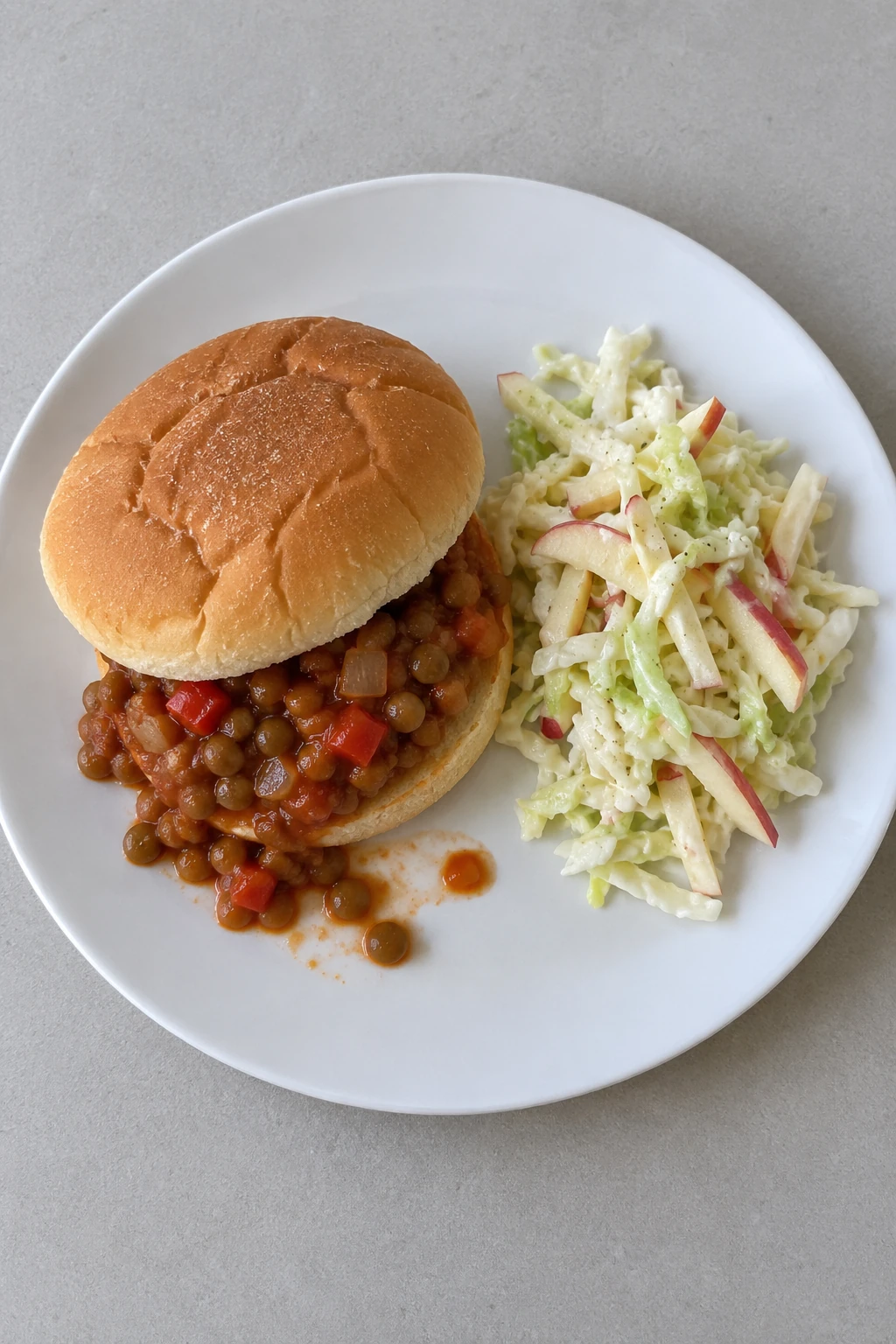 Hamburger bun with thick green-lentil/tomato filling, cabbage/apple slaw alongside; no cheese.